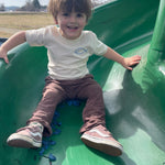 Child wearing Flow Your Own Way shirt on a slide