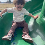 Child wearing Flow Your Own Way shirt on a slide