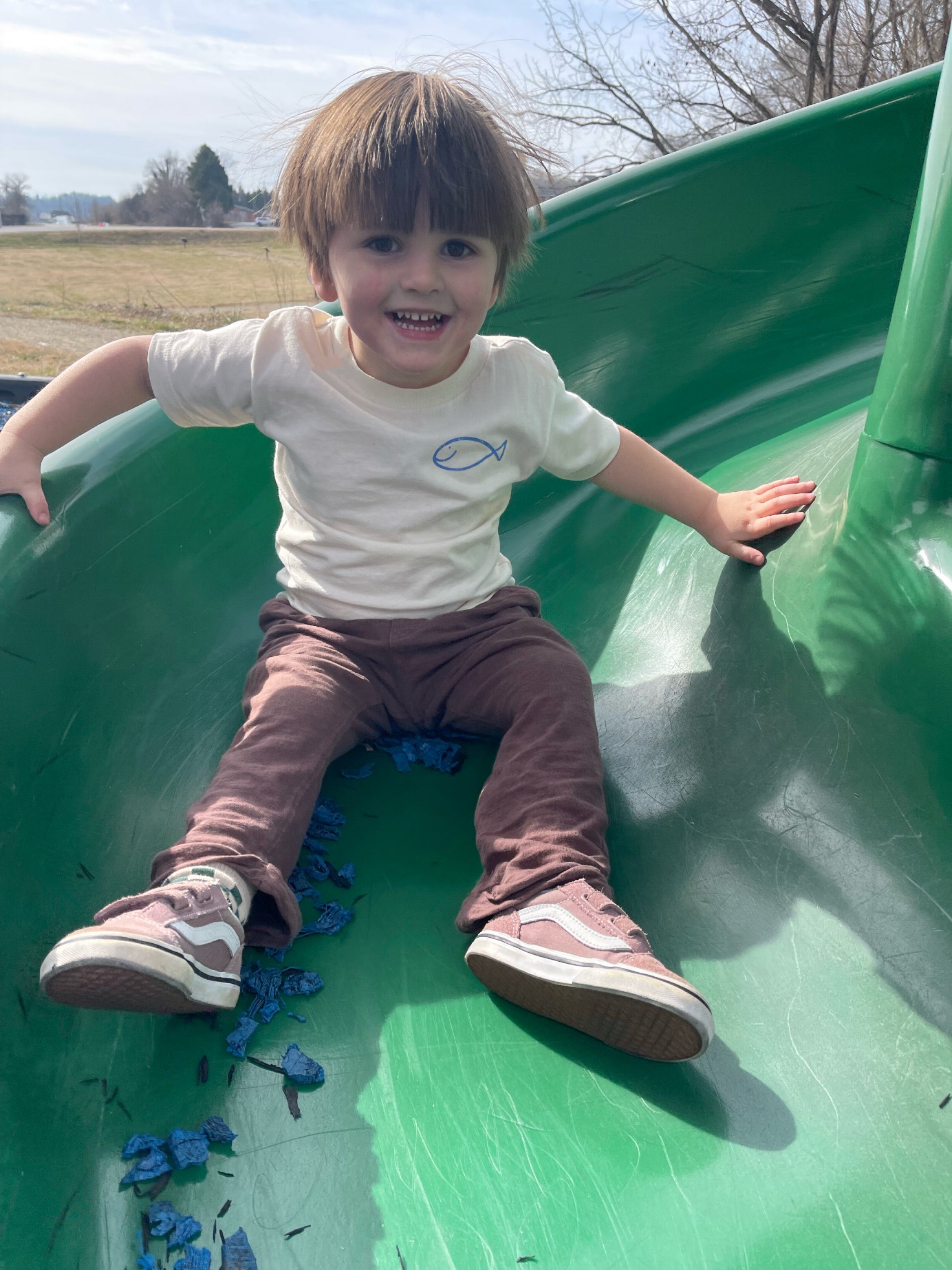 Child wearing Flow Your Own Way shirt on a slide